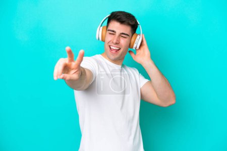Foto de Joven caucásico aislado sobre fondo azul escuchando música y cantando - Imagen libre de derechos