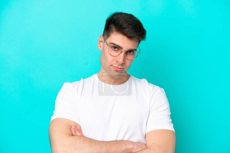 Photo for Young caucasian man isolated on blue background With glasses and arms crossed - Royalty Free Image