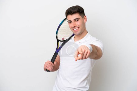 Téléchargez les photos : Jeune joueur de tennis homme isolé sur fond blanc pointant devant avec expression heureuse - en image libre de droit