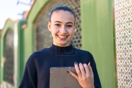 Photo for Young moroccan girl  at outdoors holding a tablet with happy expression - Royalty Free Image