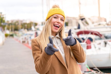 Photo for Young pretty blonde woman wearing winter jacket at outdoors pointing to the front and smiling - Royalty Free Image