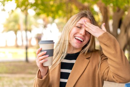 Téléchargez les photos : Jeune jolie femme blonde tenant un café à emporter à l'extérieur a réalisé quelque chose et l'intention de la solution - en image libre de droit