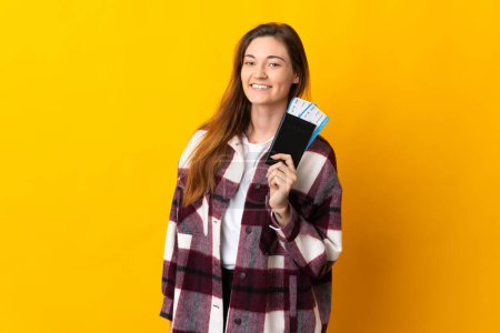Photo for Young Ireland woman isolated on yellow background happy in vacation with passport and plane tickets - Royalty Free Image