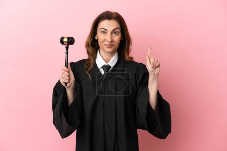 Foto de Juez de mediana edad mujer aislada sobre fondo rosa apuntando a una gran idea - Imagen libre de derechos