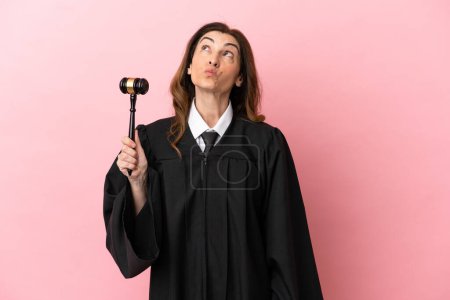 Téléchargez les photos : Juge d'âge moyen femme isolée sur fond rose et regardant vers le haut - en image libre de droit