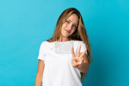 Photo for Young blonde woman isolated on blue background happy and counting three with fingers - Royalty Free Image