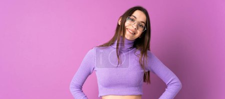 Photo for Young woman over isolated purple background posing with arms at hip and smiling - Royalty Free Image