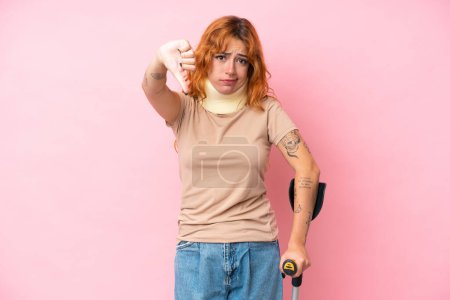 Photo for Young caucasian woman wearing neck brace isolated on pink background showing thumb down with negative expression - Royalty Free Image
