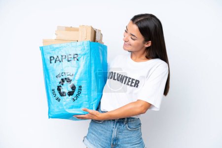 Téléchargez les photos : Jeune femme caucasienne tenant un sac de recyclage plein de papier à recycler isolé sur fond blanc avec une expression heureuse - en image libre de droit