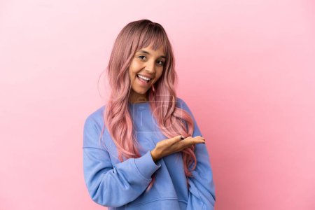 Photo for Young mixed race woman with pink hair isolated on pink background presenting an idea while looking smiling towards - Royalty Free Image