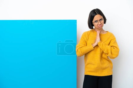 Photo for Young mixed race woman with a big blue placard isolated on white background keeps palm together. Person asks for something - Royalty Free Image
