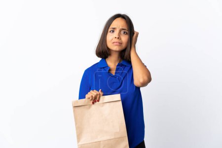Photo for Young latin woman holding a grocery shopping bag isolated on white background having doubts - Royalty Free Image