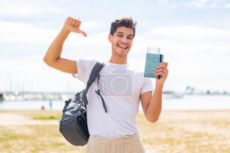 Foto de Joven caucásico con pasaporte al aire libre orgulloso y satisfecho - Imagen libre de derechos