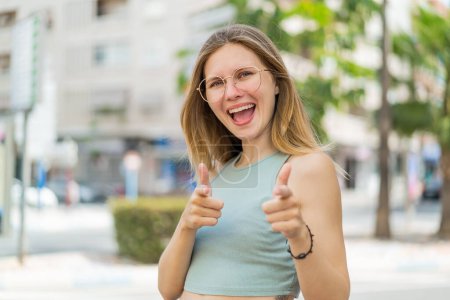 Photo for Young blonde woman with glasses at outdoors pointing to the front and smiling - Royalty Free Image