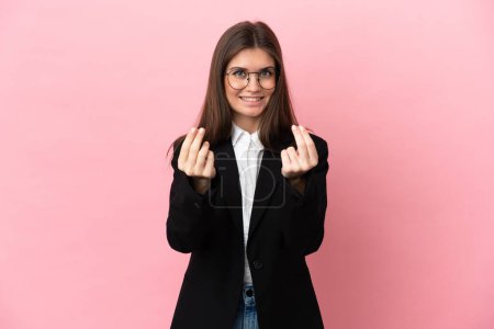 Foto de Joven negocio caucásico mujer aislado en rosa fondo haciendo dinero gesto - Imagen libre de derechos