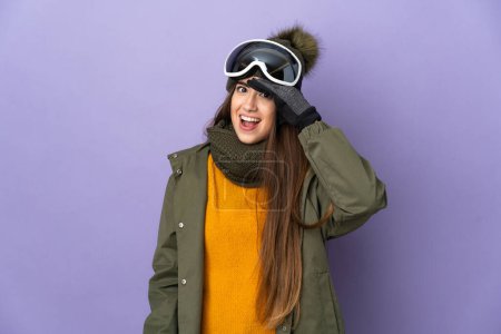 Photo for Skier caucasian girl with snowboarding glasses isolated on purple background doing surprise gesture while looking to the side - Royalty Free Image
