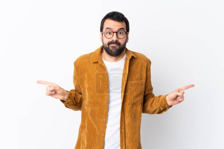 Photo for Caucasian handsome man with beard wearing a corduroy jacket over isolated white background pointing to the laterals having doubts - Royalty Free Image
