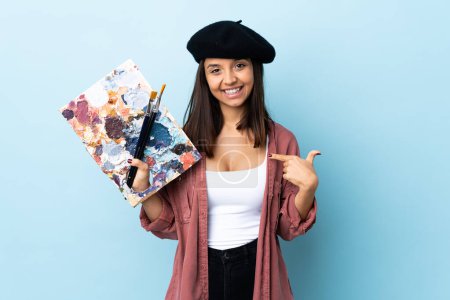 Photo for Young artist woman holding a palette over isolated blue background proud and self-satisfied. - Royalty Free Image