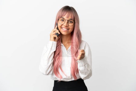Téléchargez les photos : Jeune femme de race mixte d'affaires avec les cheveux roses tenant un mobile isolé sur fond rose serrant la main pour conclure une bonne affaire - en image libre de droit
