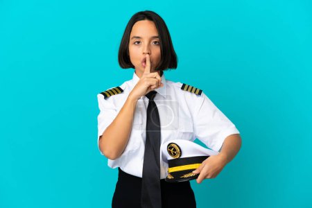Photo for Young airplane pilot over isolated blue background showing a sign of silence gesture putting finger in mouth - Royalty Free Image
