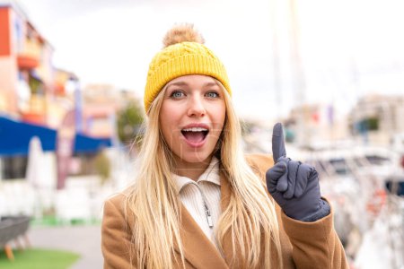 Photo for Young pretty blonde woman wearing winter jacket at outdoors thinking an idea pointing the finger up - Royalty Free Image