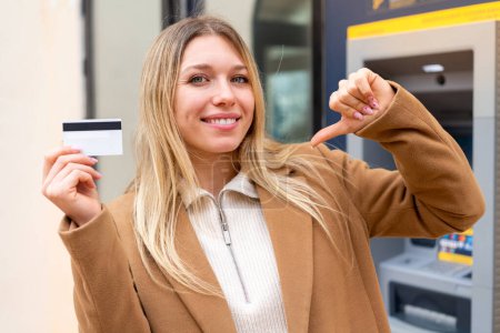 Photo for Young pretty blonde woman holding a credit card at outdoors proud and self-satisfied - Royalty Free Image