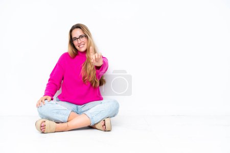 Photo for Young caucasian woman sitting on the floor isolated on white background showing and lifting a finger - Royalty Free Image