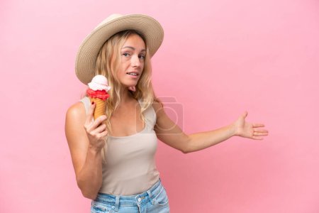 Photo for Young Russian woman holding an ice cream isolated on pink background extending hands to the side for inviting to come - Royalty Free Image