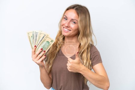 Foto de Young Russian woman taking a lot of money isolated on white background giving a thumbs up gesture - Imagen libre de derechos