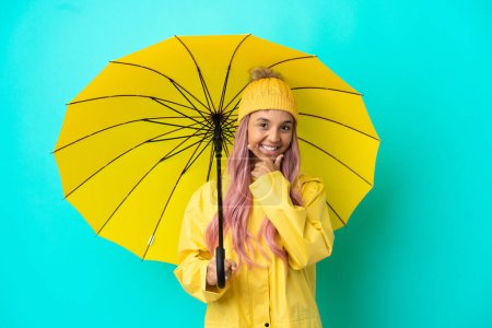 Young mixed race woman with rainproof coat and umbrella happy and smiling