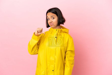 Young latin woman wearing a rainproof coat over isolated background proud and self-satisfied