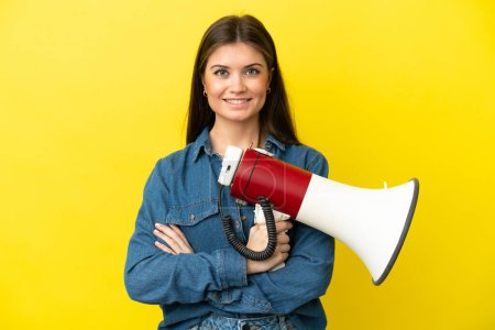 Photo for Young caucasian woman isolated on yellow background holding a megaphone and smiling - Royalty Free Image