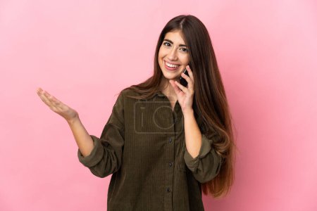 Téléchargez les photos : Jeune femme caucasienne isolée sur fond rose gardant une conversation avec le téléphone portable avec quelqu'un - en image libre de droit