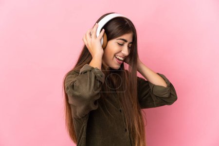 Foto de Joven mujer caucásica aislada sobre fondo rosa escuchando música - Imagen libre de derechos