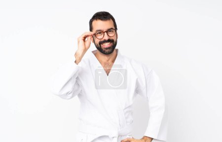 Foto de Joven haciendo karate sobre fondo blanco aislado con gafas y feliz - Imagen libre de derechos