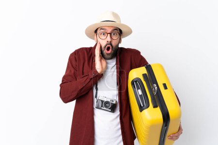 Photo for Traveler man man with beard holding a suitcase over isolated white background with surprise and shocked facial expression - Royalty Free Image