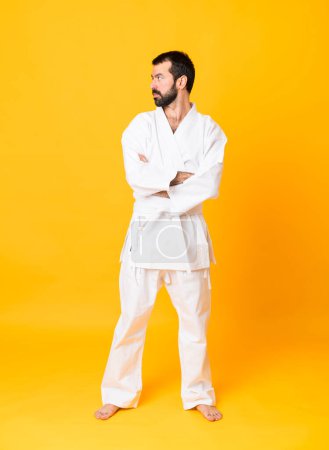 Téléchargez les photos : Full-length shot of man over isolated yellow background doing karate keeping the arms crossed - en image libre de droit