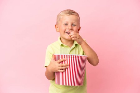 Téléchargez les photos : Petit garçon russe mangeant des popcorns dans un grand bol sur fond isolé - en image libre de droit