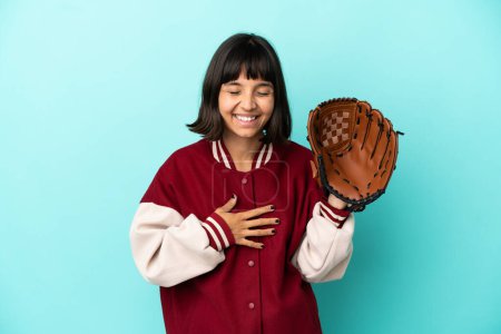 Foto de Joven mujer jugador de raza mixta con guante de béisbol aislado sobre fondo azul sonriendo mucho - Imagen libre de derechos