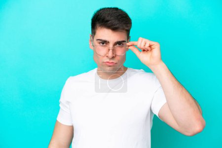 Photo for Young caucasian man isolated on blue background With glasses and frustrated expression - Royalty Free Image