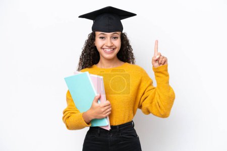 Photo for Arab university graduate woman holding books isolated on white background pointing up a great idea - Royalty Free Image