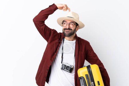Photo for Traveler man man with beard holding a suitcase over isolated white background having doubts while scratching head - Royalty Free Image