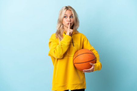 Photo for Young Russian woman playing basketball isolated on blue background showing a sign of silence gesture putting finger in mouth - Royalty Free Image