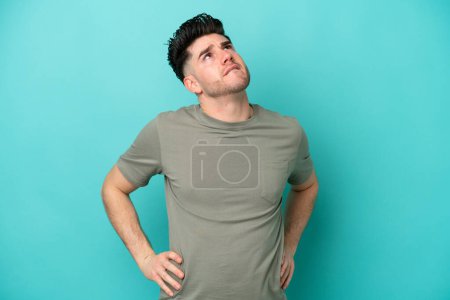 Téléchargez les photos : Jeune homme caucasien isolé sur fond bleu souffrant de maux de dos pour avoir fait un effort - en image libre de droit