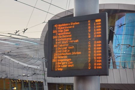Téléchargez les photos : Information panel with Dutch bus departure times in front of the central railway station in Arnhem, The Netherlands - en image libre de droit