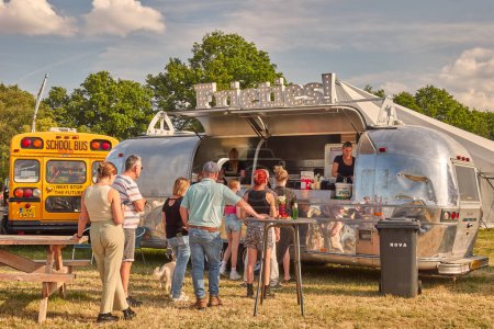 Téléchargez les photos : Aalten, Pays-Bas - 23 juin 2023 : caravane de camions de nourriture vintage vendant des frites de pommes de terre avec des personnes commandant sur une foire nationale à Aalten, Pays-Bas - en image libre de droit