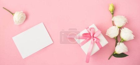 Photo for Empty white paper for text, gift box and beautiful white flowers on the pink  background. Top view. Copy space. - Royalty Free Image