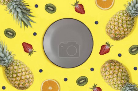 Foto de Empty gray plate for text, fruit and berry on the yellow background. Copy space. Top view. - Imagen libre de derechos