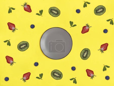 Foto de Empty gray plate for text, fruit and berry on the yellow background. Top view. - Imagen libre de derechos