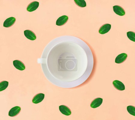 Photo for Empty white cup for tea and mint on the orange background. Close-up. Top view. - Royalty Free Image